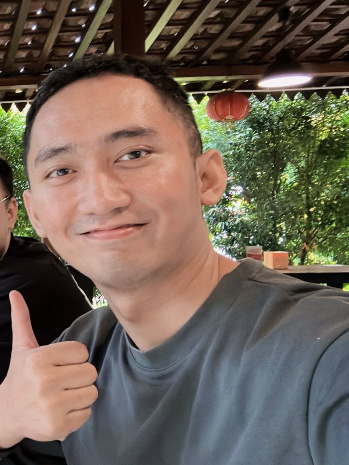 Adryan giving a thumbs up at a garden cafe
